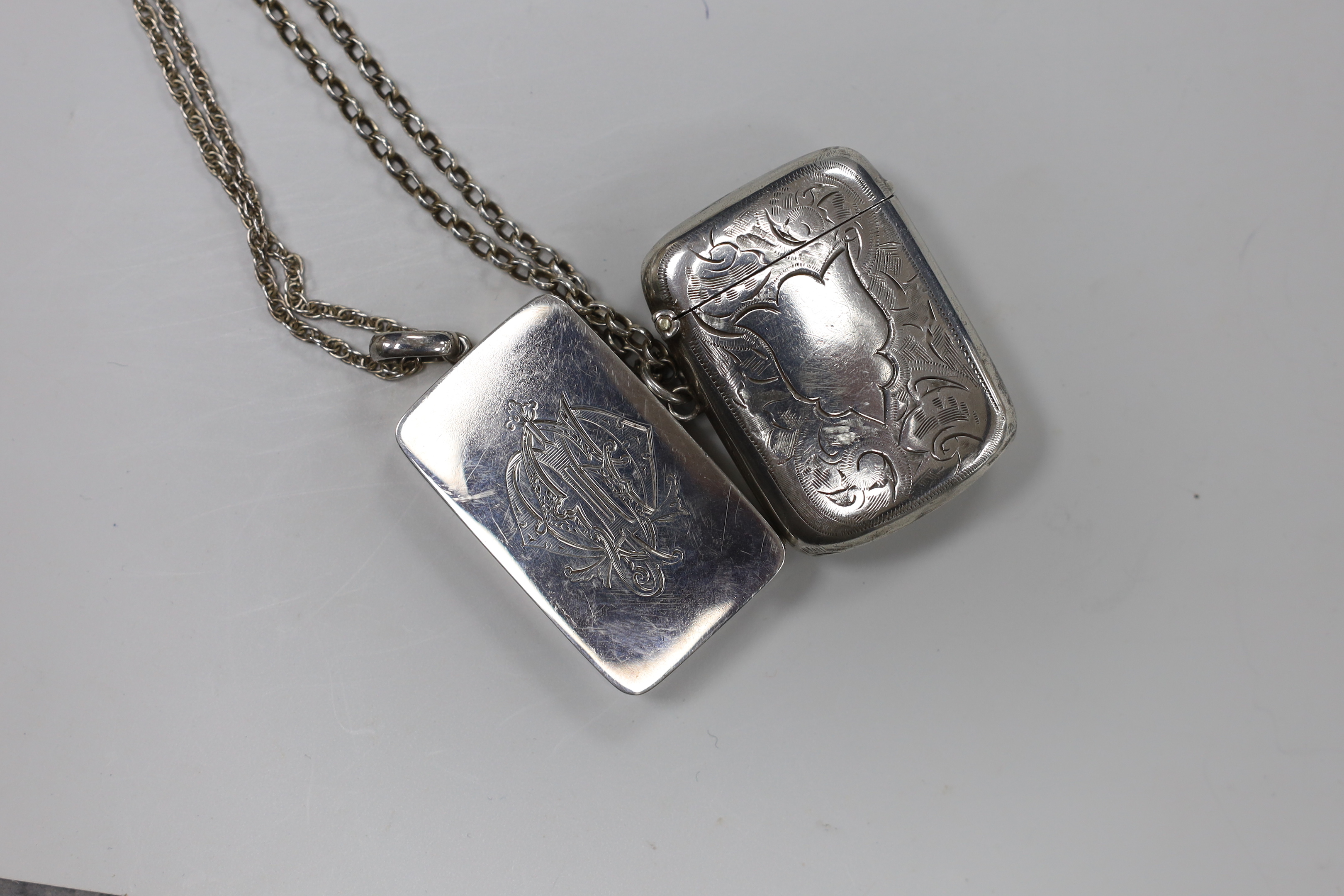 A Japanese parcel gilt white metal rectangular locket (interior crack), 46mm, on a white metal chain and a George V silver vesta case, on a sterling chain.